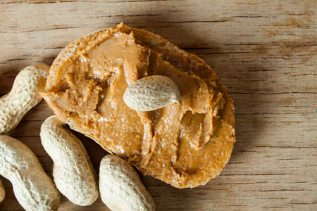 Peanut butter and roasted peanuts on wood desk