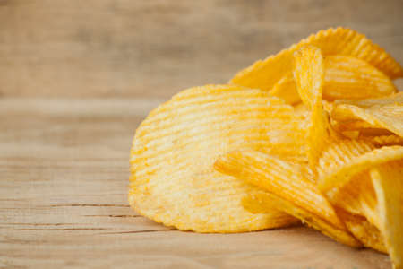 Fried potato chips corrugated on wood desk. Food