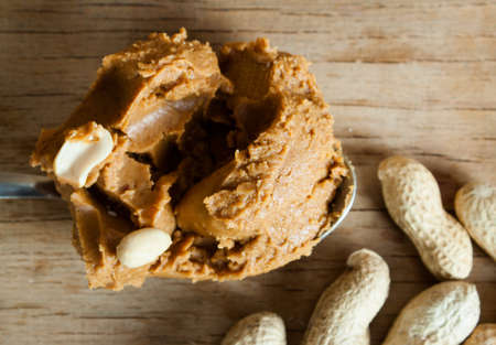 Peanut butter and roasted peanuts on wood desk
