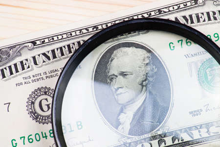 Dollar banknote and glass magnifying on wood desk.の写真素材