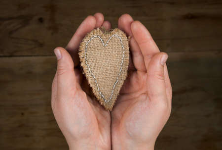 Heart from cloth in hand on wood desk. Valentines day backgroundの写真素材