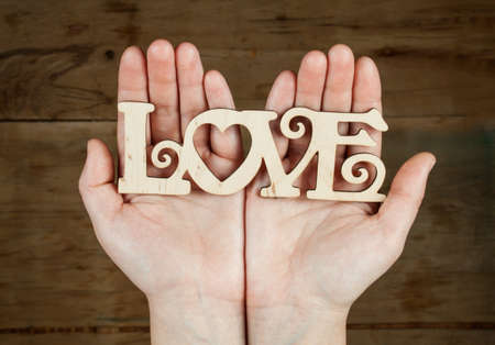 Inscription love in hand on wood desk. Valentines day backgroundの写真素材