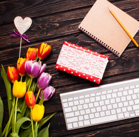 Fresh tulips with keyboards on wood desk.の写真素材