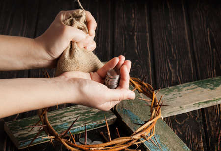 Crown of thorns with hands and coins on wood desk. Christian conceptの写真素材