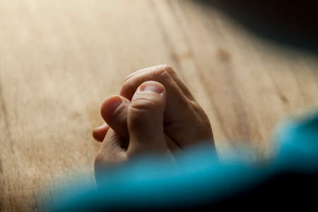 Child hands folded for prayer on wood tableの写真素材
