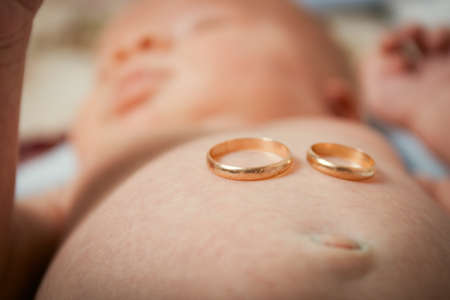 Legs of an infant with wedding rings. The concept of the family