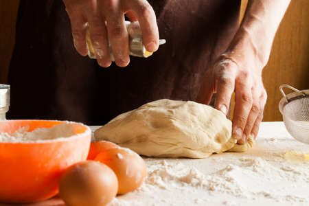 Man cooks in the kitchen preparing dough. Cooking process