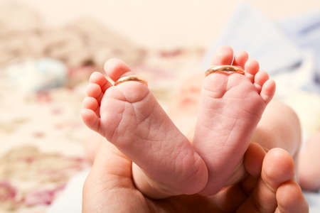 Legs of an infant with wedding rings. The concept of the familyの写真素材