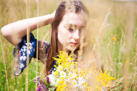 Fashion beautiful girl in the field with bouquet of wildflowersの写真素材
