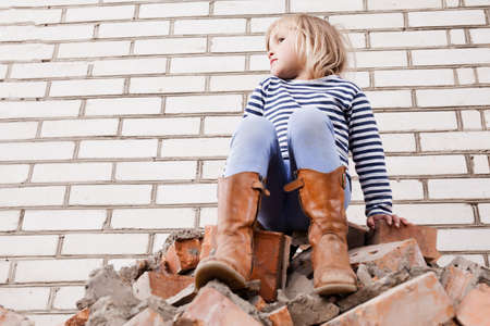 Happy little girl in hat outside on brick backgroundの写真素材