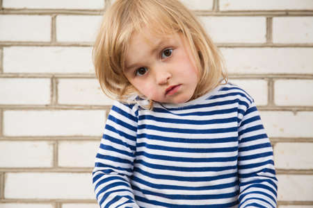 Happy little girl in hat outside on brick backgroundの写真素材