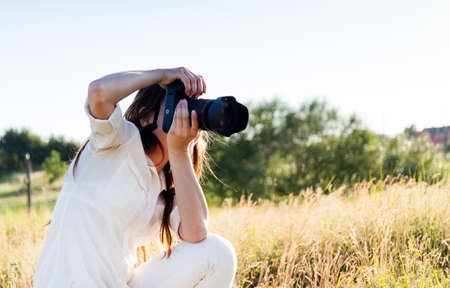 Young woman outdoors portrait with camera. Soft sunny colors.の写真素材