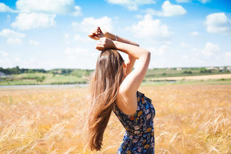 Fashion beautiful girl in the field with yellow spikelets on the sky backgroundの写真素材