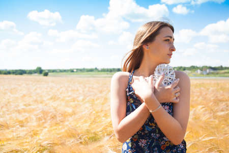 Fashion beautiful girl in the field with yellow spikelets on the sky background