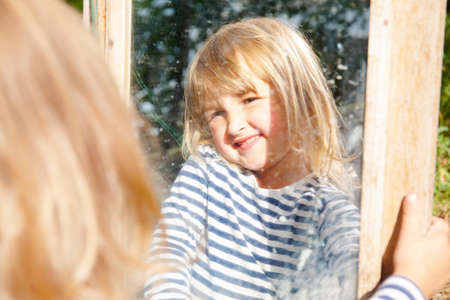 Happy little girl outside in nature with mirrorの写真素材