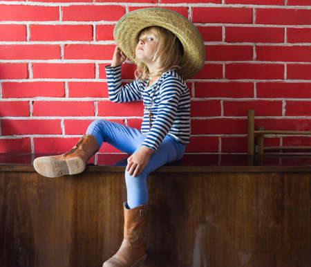 Happy little girl in hat on brick backgroundの写真素材