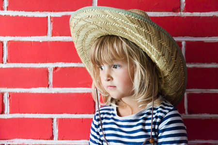 Happy little girl in hat on brick backgroundの写真素材