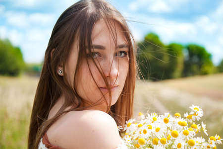 Fashion beautiful girl in the field with bouquet of wildflowersの写真素材