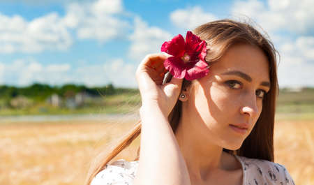 Fashion beautiful girl in the field with yellow spikelets on the sky backgroundの写真素材