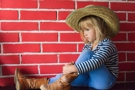 Happy little girl in hat on brick backgroundの写真素材