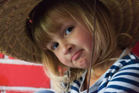 Happy little girl in hat on brick background