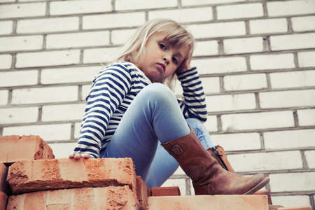 Happy little girl in hat outside on brick backgroundの写真素材