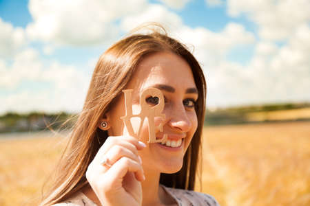 Fashion beautiful girl in the field with yellow spikelets on the sky backgroundの写真素材
