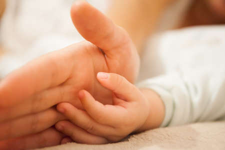 Mom holds the baby's hand.の写真素材