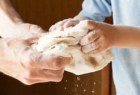 Hands knead the dough. Baby and adult hands. Collaborationの写真素材