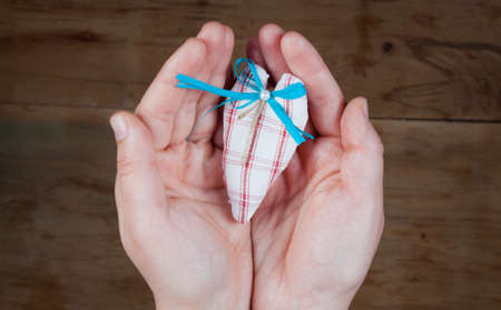 Heart from cloth in hand on wood background. Happy Valentines Day
