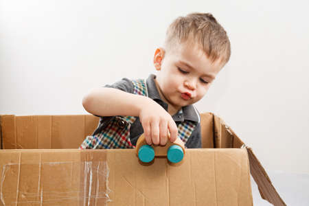 Little boy with wood car in paper box. problems with own housing and carの写真素材
