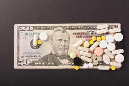 Pills and dollar banknote on black backgroundの写真素材