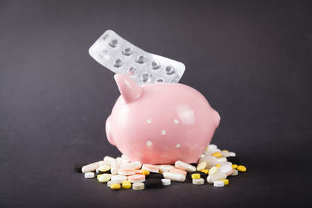 Pills and pig money box on black backgroundの写真素材