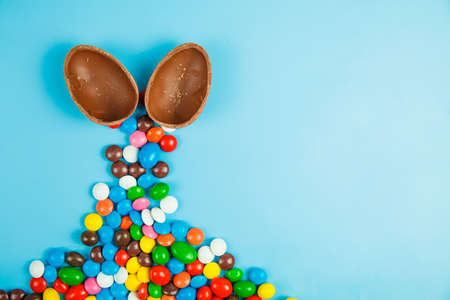 Chocolate eggs and glaze color candy on blue background. Happy easter