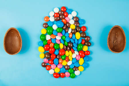 Chocolate eggs and glaze color candy on blue background. Happy easterの写真素材