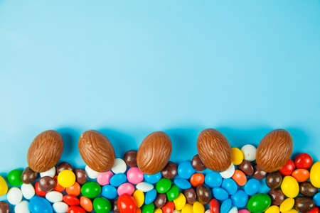 Chocolate eggs and glaze color candy on blue background. Happy easterの写真素材