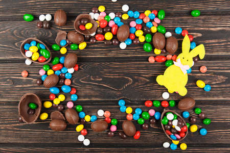 Chocolate eggs and glaze color candy on wood desk. Happy easterの写真素材