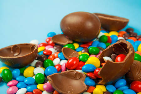 Chocolate eggs and glaze color candy on blue background. Happy easter