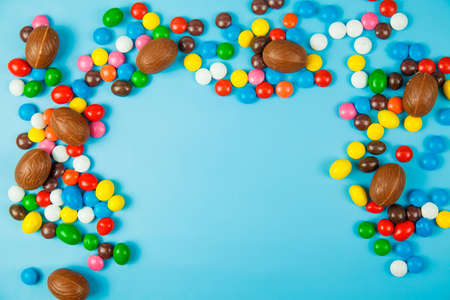 Chocolate eggs and glaze color candy on blue background. Happy easterの写真素材