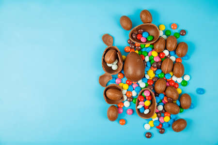 Chocolate eggs and glaze color candy on blue background. Happy easterの写真素材