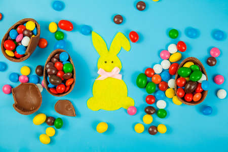 Chocolate eggs and glaze color candy on blue background. Happy easterの写真素材