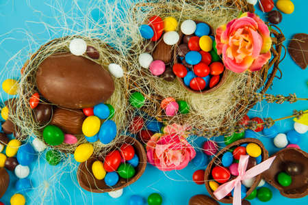 Chocolate eggs and glaze color candy on blue background. Happy easter