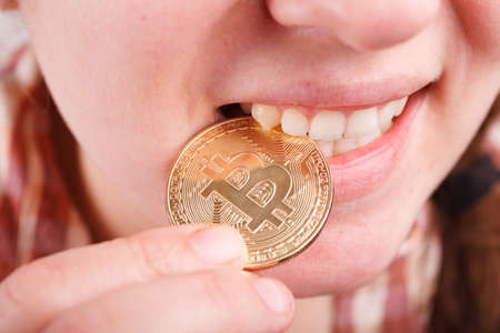 crazy bitcoin lover with golden coin by eyes; funny miner with btc near faceの写真素材
