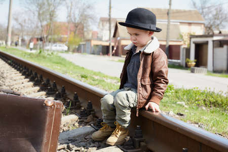 Little boy with suit case on railway out door. Travel conceptの写真素材