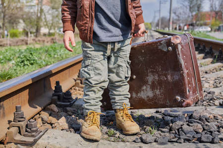 Little boy with suit case on railway out door. Travel conceptの写真素材