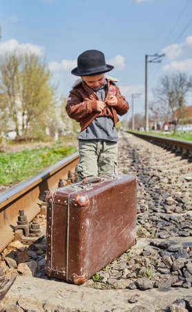 Little boy with suit case on railway out door. Travel conceptの写真素材