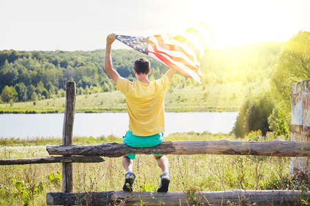Man with the flag of the United States of America, against the sky with sunset. Independence Day, patriot, military.の写真素材