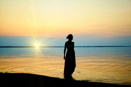 Woman on beach. Sunset at sea. Nature backgroundの写真素材