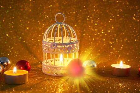 Burning candle and Christmas decoration over snow and wooden background, elegant low-key shot with festive moodの写真素材