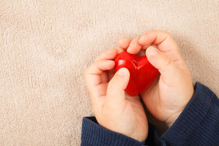 child hands holding red heart, health care, love and family concept, world heart day